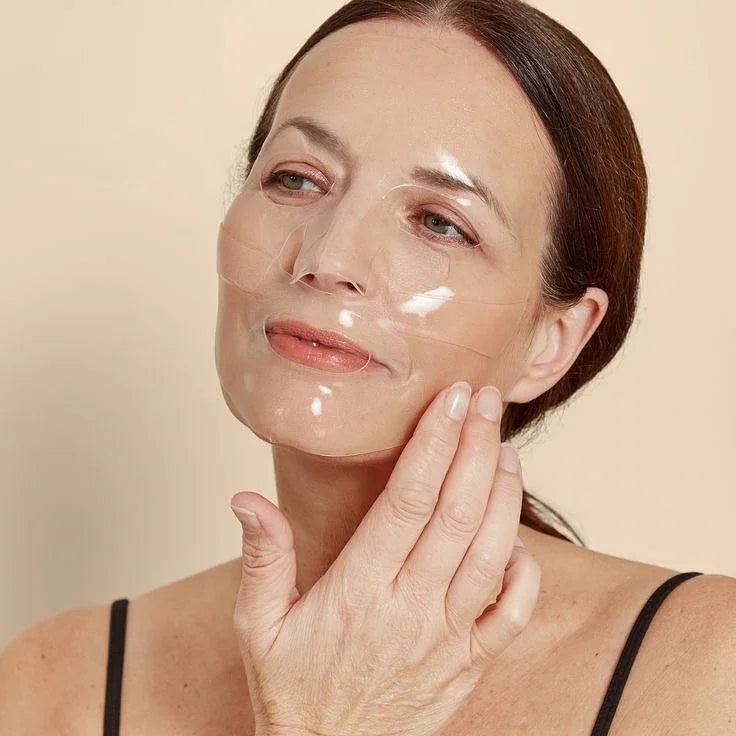 Middle-aged woman applying transparent hydrogel collagen face mask for deep skin hydration